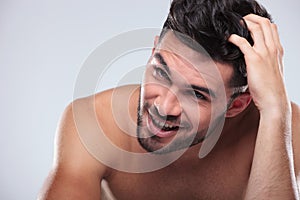 Happy naked man scratching his head and smiles