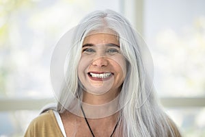 Happy naturally grey haired senior Latin woman head shot portrait