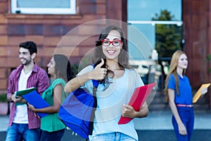 Happy nerdy female student with group of young adults