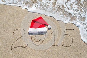 Happy new year 2015 with smiley face in santa hat on sandy beach