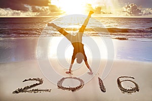 Happy new year 2016. young man handstand on the beach