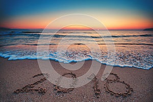 Happy New Year 2018 concept, lettering on the beach. Sea sunrise