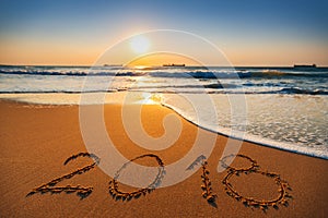 Happy New Year 2018 concept, lettering on the beach. Sea sunrise