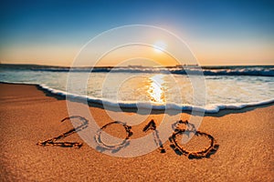 Happy New Year 2018 concept, lettering on the beach. Sea sunrise