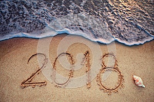 Happy New Year 2018 concept, lettering on the beach. Sea sunrise