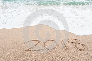 Happy new year 2018 concept. Number 2018 written on sandy beach