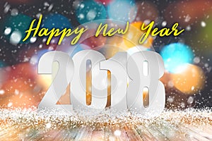 Happy New year 2018 text above empty wood table with snowfall and bokeh light background