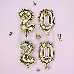 Happy New year 2020 celebration concept. Gold foil balloons numeral 2020 and golden stars on pastel pink background