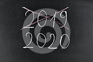 Happy new year 2020. Chalkboard with 2020, crossed 2019 and hand with chalk