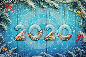 Happy New Year 2020 holiday background. Set of transparent numbers made of glass filled with multicolored candy and sweets hang on