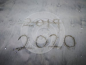 Happy new year 2020, lettering on the beach with wave and clear blue sea. Numbers 2020 year on the sea shore.