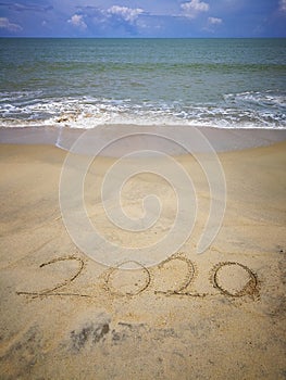 Happy new year 2020,lettering on the beach with wave and clear blue sea. Numbers 2020 year on the sea shore. Beautiful beach.