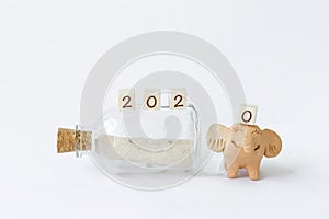Happy New Year 2020 on message bottle and smiling happy elephant clay doll