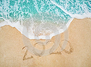 Happy New Year 2020 written on seashore sand at sunrise concept.beautiful sandy beach and soft blue ocean wave