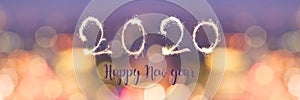Happy new year 2020 written with sparkles on panoramic banner of blurred bokeh holiday lights