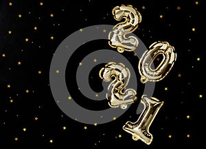 Happy New year 2021 celebration. Gold foil balloons numeral 2021 and gold confetti on black background. New year concept.