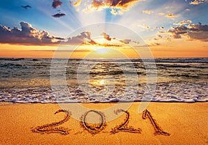 Happy New Year 2021 is coming concept. Number 2021 written on seashore sand.