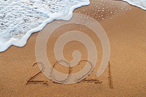 Happy New Year 2021 concept, lettering on the beach. Written text on the sea beach at sunrise