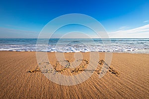 Happy New Year 2021 concept, lettering on the beach. Written text on the sea beach at sunrise