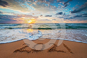 Happy New Year 2021 concept, lettering on the beach. Written text on the sea beach at sunrise