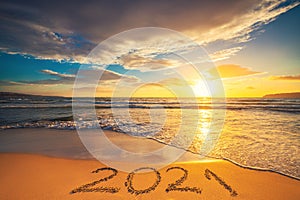 Happy New Year 2021 concept, lettering on the beach. Written text on the sea beach at sunrise