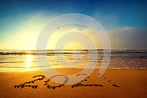 Happy New Year 2021 concept, lettering on the beach. Written text on the sea beach at sunrise