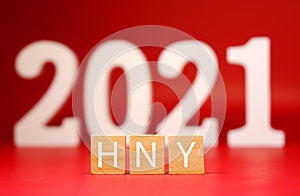 Happy New year 2021 , HNY word on wooden block and blur 2021 on red background - red new year celebrate advertising concept