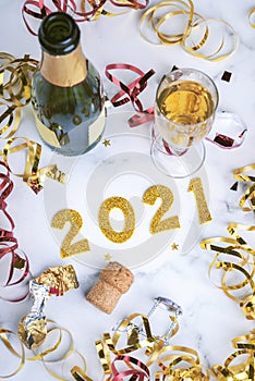 Happy New Year 2021. New Years Eve celebration concept background.Champagne bottle with glass and confetti