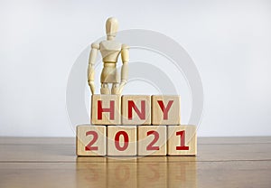 Happy New Year 2021 symbol. Concept words `HNY 2021 - Happy New Year 2021` on cubes on a beautiful wooden table. Wooden model of