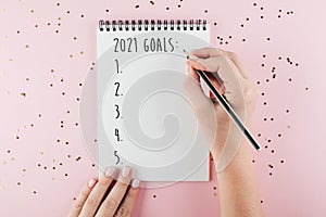 Happy New Year 2021. Woman`s hand writing 2021 Goals in notebook