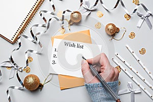 Happy New Year 2021. Woman`s hand writing in notebook decorated with Christmas decorations on the grey background. Top view, flat