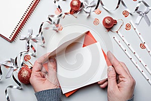 Happy New Year 2021. Woman`s hand writing in notebook decorated with Christmas decorations on the grey background. Top view, flat