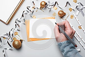 Happy New Year 2021. Woman`s hand writing in notebook decorated with Christmas decorations on the grey background. Top view, flat