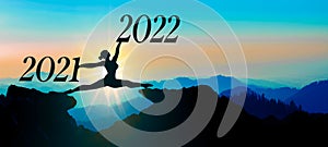 Happy new Year 2022 background banner panorama - A young ballerina woman does a split jump between 2021 and 2022 years over the