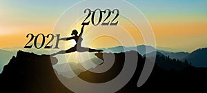 Happy new Year 2022 background banner panorama - A young woman does a split jump between 2021 and 2022 years over the sun and