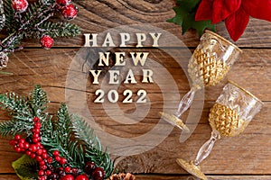 Happy New year 2022 celebration. Champagne glasses and poinsettia flower on wooden background. Flat lay