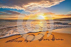 Happy New Year 2022 concept, lettering on the beach. Written text on the sea beach at sunrise
