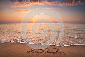Happy New Year 2022 concept, lettering on the beach. Written text on the sea sand at sunrise