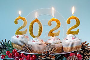 Happy New Year 2022 cupcakes with lighting candles. Merry Christmas and winter season greetings concept. Copy space