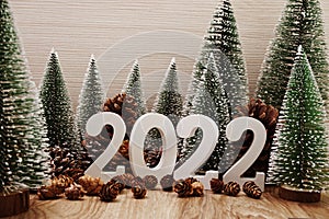 Happy New Year 2022 festive background with christmas tree and pine cone decoration on wooden background