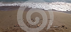 Happy New Year 2022, lettering on the beach with wave and clear blue sea.