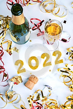 Happy New Year 2022. New Years Eve celebration concept background.Champagne bottle with glass and confetti