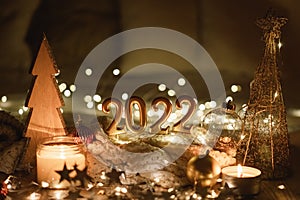Happy New Year 2022. Number 2022 made by candles on a festive sparkling bokeh background in the dark
