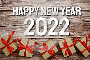 Happy New Year 2022 typography text with gift box on wooden background