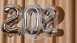 Happy new year 2023 change to 2024 metallic balloons on atlas textile background. Greeting card silver foil balloons