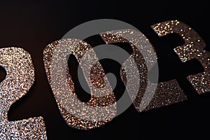 Happy New Year 2023. Golden numbers on a black background with glitter