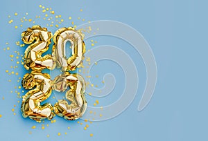 Happy New Year 2023 greeting card. 2023 golden foil balloons numbers and confetti. Top horizontal view copy space new year and