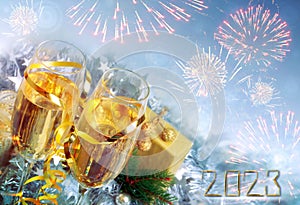 Happy new year 2023 greeting card with two champagne glasses and fireworks.