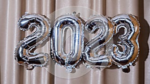 Happy new year 2023 metallic balloons on atlas textile background. Greeting card silver foil balloons numbers Christmas