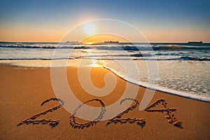 Happy New Year 2024 concept, lettering on the beach. Sea sunrise